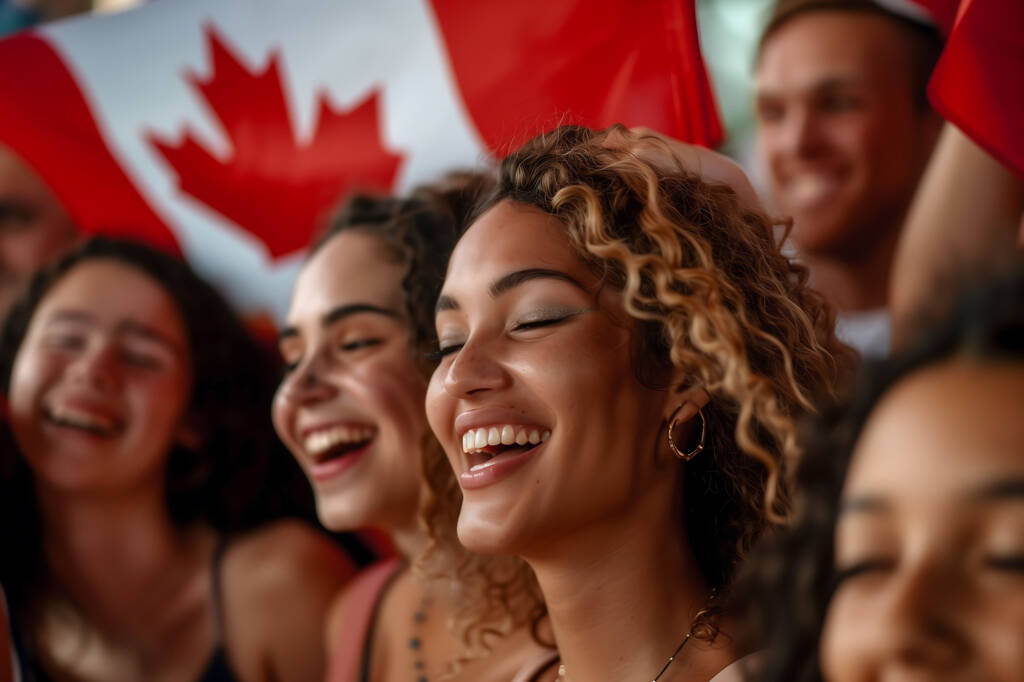 Image of immigrants standing in front of a canadian flag and smiling