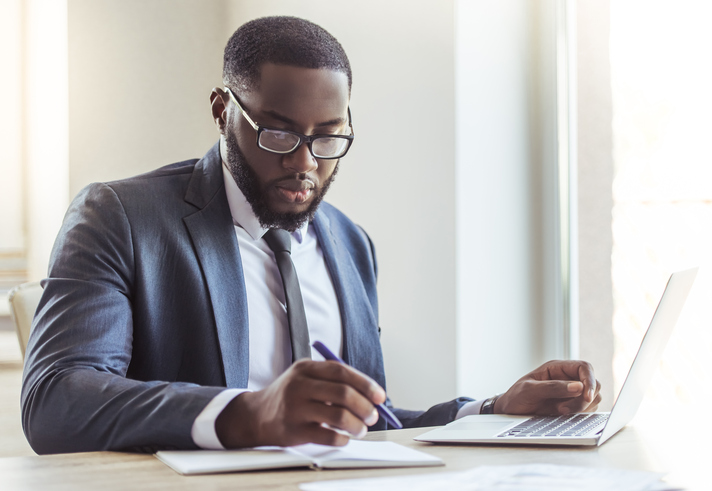 Image of a African American man doing research on a laptop