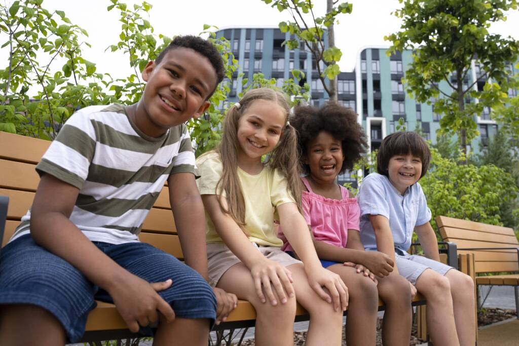 Image of children sitting on a bench representing immigrants getting settled in a new school and country